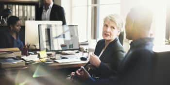 Three people chatting in an office about performance management.