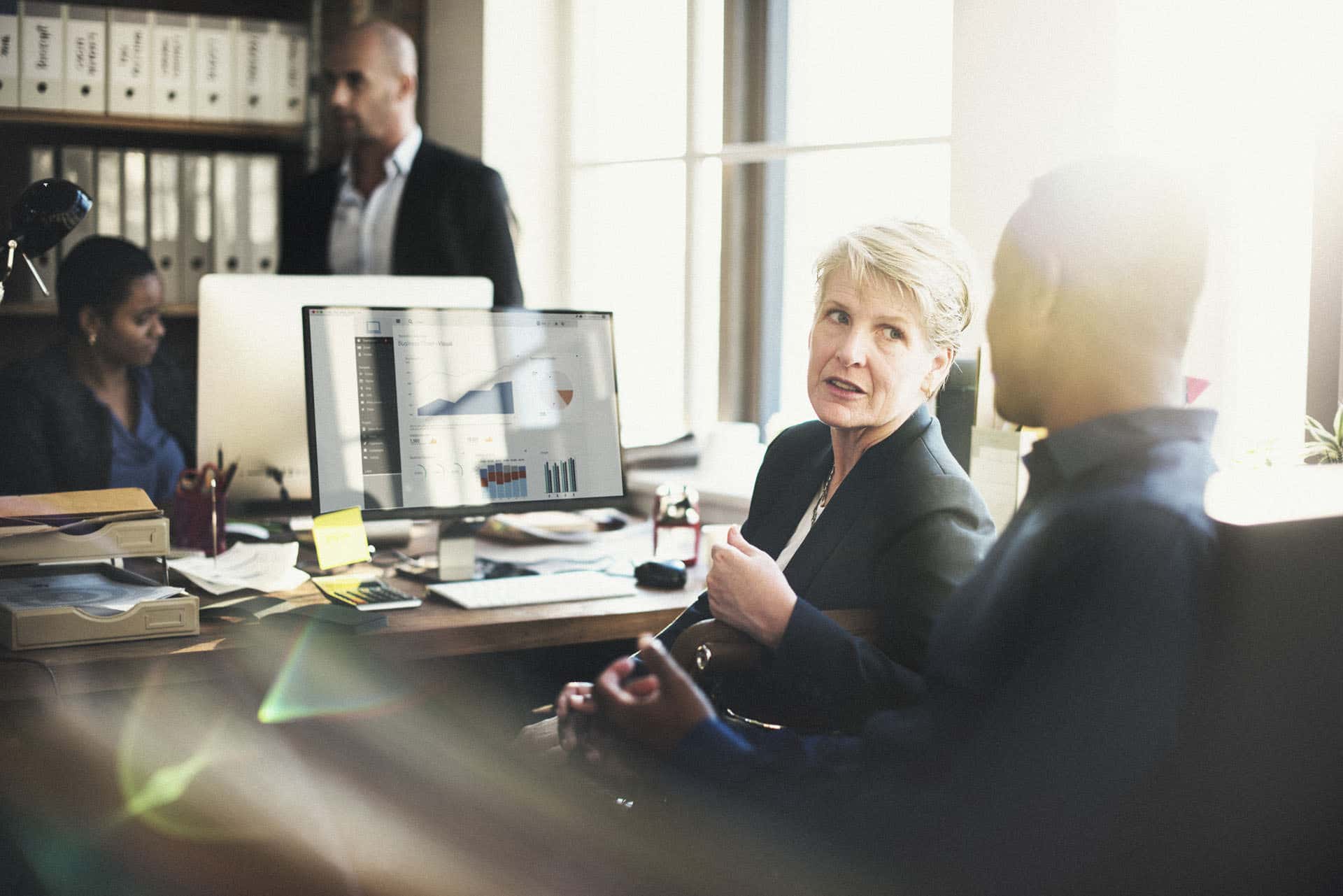 Three people chatting in an office about performance management.